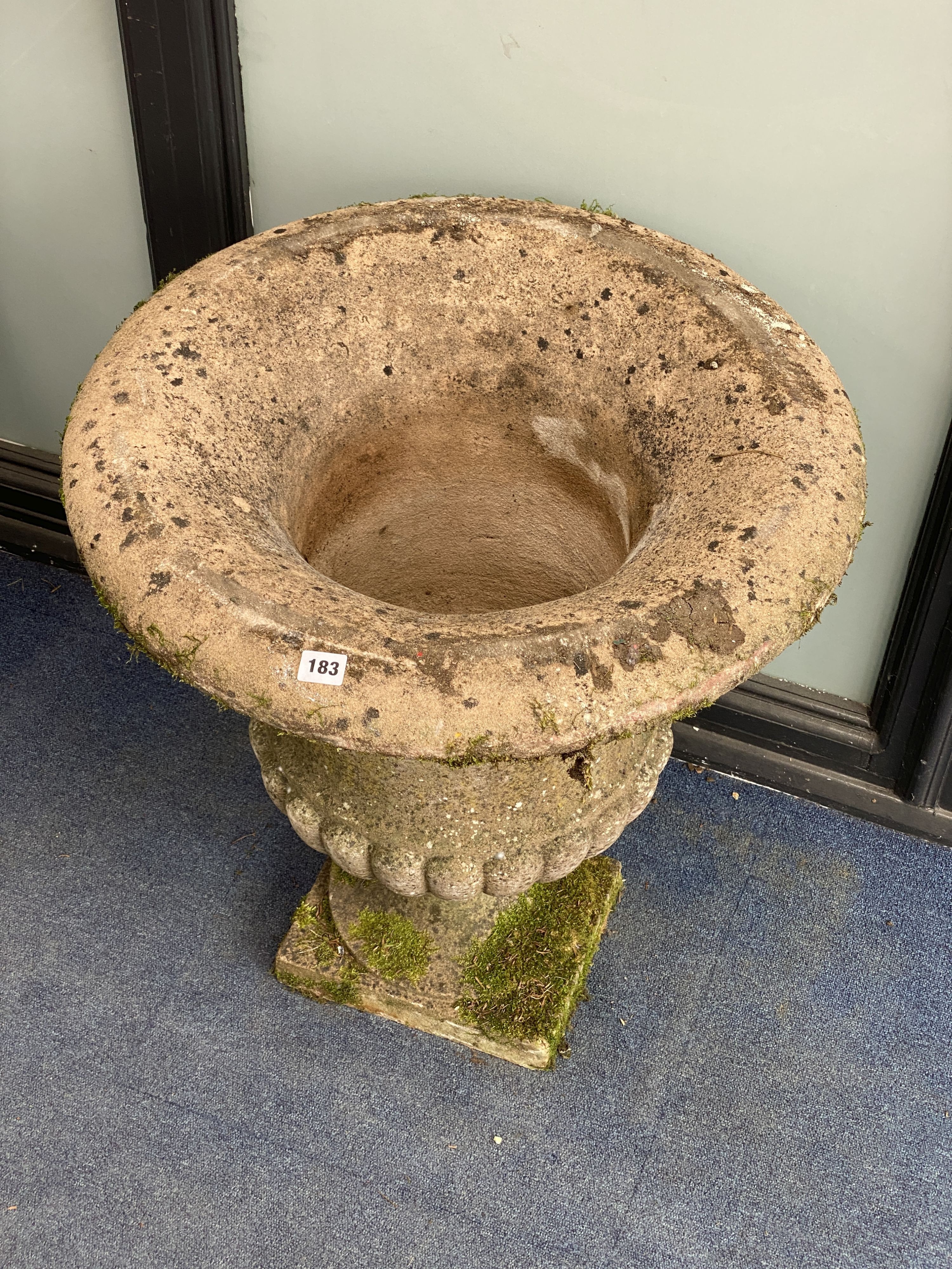 A reconstituted stone fluted campana shaped garden urn, diameter 62cm, height 70cm on square plinth